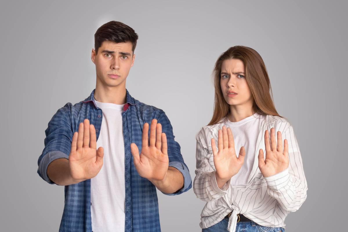 Dissatisfied and upset young man and woman gestures and fenced off with their hands and look at camera