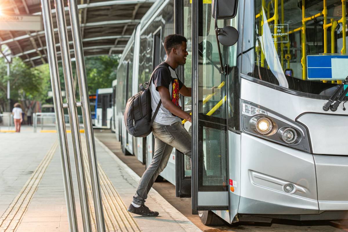 A black boy or student of afro descent, walking up on a municipal bus